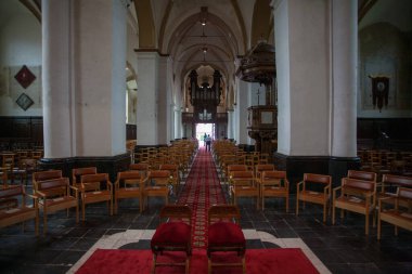 El yapımı ahşap sandalyeler ve sunağa uzanan canlı kırmızı bir halı olan sakin bir kilise.