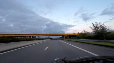 Huzurlu ve sakin bir otoyol manzarası. Parlak sarı bir üst geçit. Güzel, karanlık bir gökyüzüne karşı kurulmuş.