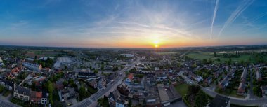 Halle, Vlaams Brabant, Belgium, 27th of April, 2025, A stunning aerial view showcases a beautiful sunset that brilliantly illuminates a peaceful suburban neighborhood