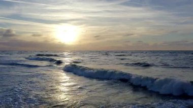 Okyanusun nefes kesen manzarası günbatımını yansıtıyor. Altın renkler, sakin dalgalar kıyıya vuruyor.