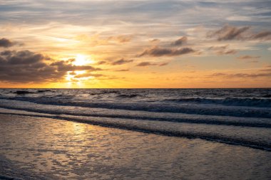 Nefes kesici bir günbatımı, yumuşak okyanus dalgalarının üzerinde hafifçe süzülen canlı ve parlak renkler ile gökyüzünü boyamaktır.