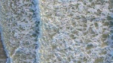 Aşağıdaki okyanus dalgalarının dinamik ve büyüleyici desenlerini yakalayan nefes kesici bir hava manzarası.