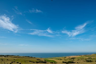 Cap Blanc-Nez, Escalles, Pas-de-Calais, Hauts-de-France, Fransa, 29 Temmuz 2025, uçsuz bucaksız mavi gökyüzünün altında yuvarlanan yeşil tepelerin çarpıcı manzarası.