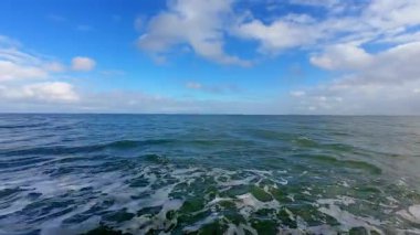 Nazik ve sakin okyanus dalgaları çarpıcı bir mavi gökyüzü ile birlikte tamamen huzurlu bir kıyı manzarası yaratır.