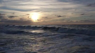 Şaşırtıcı derecede güzel bir gün batımı okyanus dalgalarına yansıyor, rahatlatıcı ve huzurlu bir atmosfer yaratıyor.