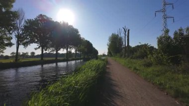 Kanal yolunda uzun ağaçlarla huzurlu bir yürüyüşün tadını çıkar. Sıcak güneş ışığını tenine yansıt.