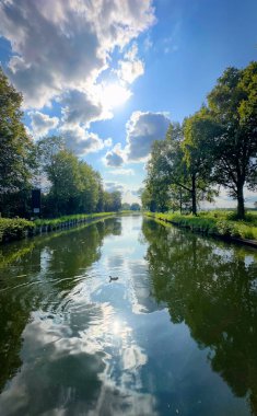 Huzurlu ve sakin bir nehir manzarası harika yansıtır ağaçları ve bulutları güzel bir gökyüzüne karşı