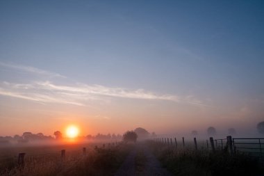 Nefes kesici bir gün doğumu sakin, sisli bir manzarayı aydınlatır. Huzurlu bir yansıma anı için mükemmeldir.