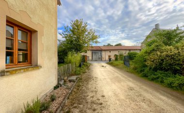 Bergnicourt, Rethel, Ardennes, Grand-Est, France, August, 28th, 2025,A beautifully serene view of a dirt pathway gently leading through picturesque rural countryside homes