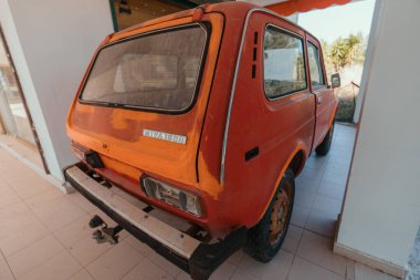 Yunanistan 'ın Corfu kentindeki bir otelin otoparkına park edilmiş kırmızı paslı eski bir araba.