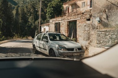 Güneşli bir günde Corfu, Yunanistan 'da şehri gezen aracın ön camından görülen araba.