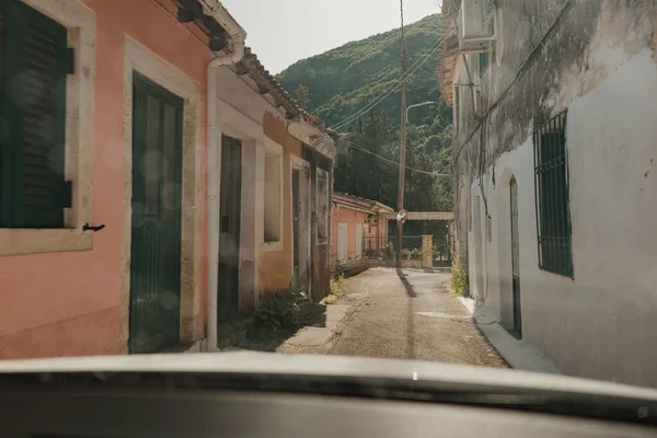 Güneşli bir günde, Corfu, Yunanistan 'da eski evler ve dar sokaklar arabaların ön camından şehri gezerken görülüyor.