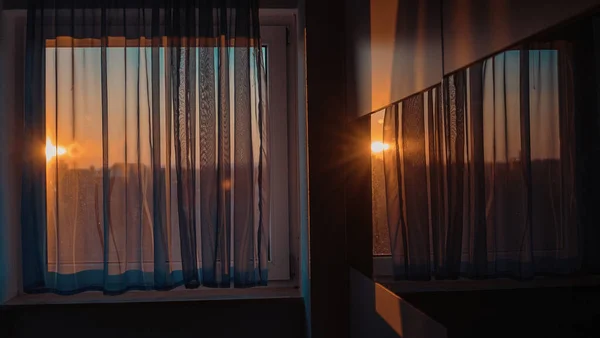日落时带窗帘和明亮阳光的窗户映照在房间的玻璃柜上 — 图库照片