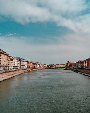 İtalya 'nın Pisa kentindeki bulutlu gökyüzüne karşı geleneksel iskan binalarından geçen güzel Arno nehrinin perspektifi giderek azalıyor