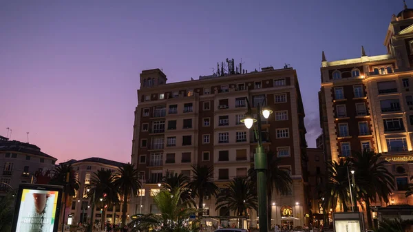 西班牙安达卢西亚马拉加市滨海广场与Unicaja Bank大楼的低视角景观 黄昏时分在晴朗的天空下点亮街灯和棕榈树 — 图库照片