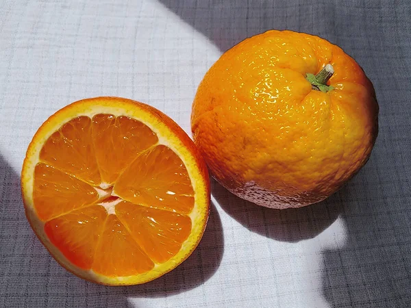 Ganze Früchte Und Geschnittene Saftige Orange Vom Sonnenlicht Erhellt Auf — Stockfoto