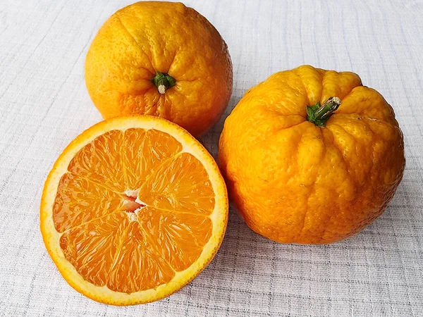 Eine Halbe Und Zwei Ganze Orangen Auf Einem Weißen Leinentisch — Stockfoto