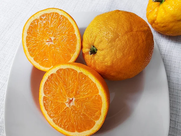 Zwei Hälften Und Ganze Orange Auf Einem Weißen Teller Nahaufnahme — Stockfoto