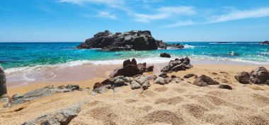 Dalgalar ve kayalarla kaplı bir deniz manzarası. Güneşli bir günde Akdeniz kıyısı. Akdeniz ve kayalar. Kum kıyısı. Yaz günü. Costa Brava. İspanya. 