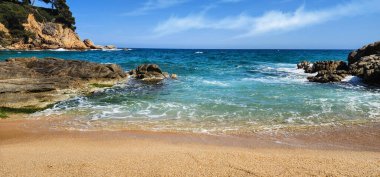Dalgalar ve kayalarla kaplı bir deniz manzarası. Akdeniz kıyıları güneşli bir günde. Akdeniz ve kayalar. Kum kıyısı. Yaz günü. Costa Brava. İspanya. 