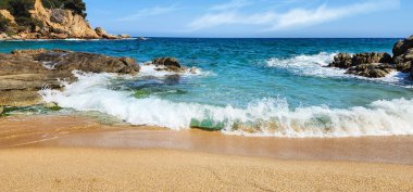 Dalgalar ve kayalarla kaplı bir deniz manzarası. Akdeniz kıyıları güneşli bir günde. Akdeniz ve kayalar. Kum kıyısı. Yaz günü. Costa Brava. İspanya. 