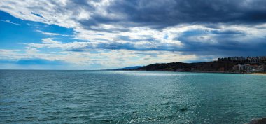 Dramatik bulutlu deniz manzarası. Güzel deniz manzarası, uzak dağlar. Yağmurdan sonra gökyüzü açılır.. 
