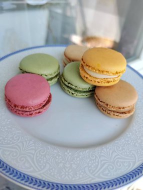 Beyaz bir tabakta bulunan renkli Fransız kurabiyeleri.