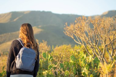 Dağda yürüyen bir kız fotoğraf çekiyor.