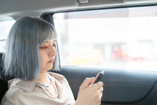 一个台湾女人开着智能手机 坐在出租车里向外面看 — 图库照片