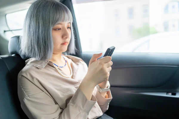 一个台湾女人开着智能手机 坐在出租车里向外面看 — 图库照片