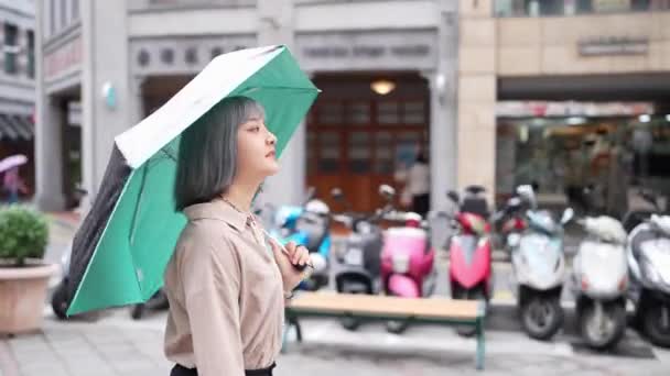 台湾一位年轻女子提着雨伞走在台北市的一条传统街道上 — 图库视频影像
