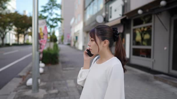 Unge Japansk Kvinne Som Går Mens Hun Snakker Smarttelefonen Sin – stockvideo