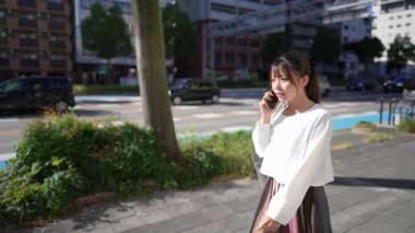 Japonya 'nın Aichi ilindeki Nagoya şehrindeki Osu alışveriş bölgesi yakınlarında akıllı telefonuyla konuşan genç bir Japon kadın..