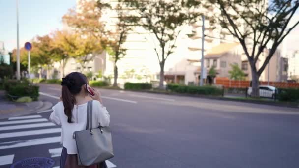 Unge Japansk Kvinne Som Går Mens Hun Snakker Smarttelefonen Sin – stockvideo
