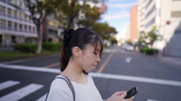 Giovane Donna Giapponese Che Cammina Mentre Utilizza Uno Smartphone Lungo — Video Stock