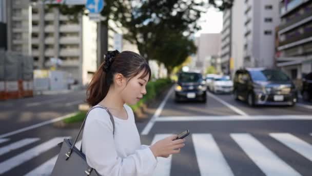 Молода Японська Жінка Ходить Під Час Роботи Смартфона Вздовж Дороги — стокове відео
