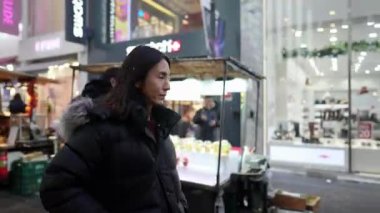 30 'lu yaşlarında Güney Koreli bir adam kışın kar yağarken Myeongdong, Seul, Güney Kore' de bir sokakta gece gezintisi yapıyor..