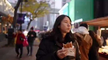 30 'lu yaşlarında Güney Koreli bir adam kışın kar yağarken Myeongdong, Seul, Güney Kore' de bir sokakta gece gezintisi yapıyor..