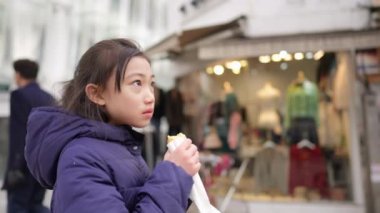 Soğuk bir kış gününde Güney Kore, Seul 'de kızarmış ekmek alan ve yiyen Koreli bir kızın yavaş çekim videosu.