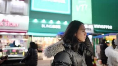 Myeong-dong, Seul, Güney Kore 'de soğuk bir gecede gece marketinden atıştırmalık alıp yiyen 30' lu yaşlarda uzun saçlı Koreli bir adam.