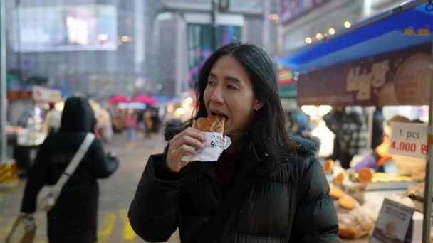 Długowłosy Koreańczyk Trzydziestce Który Kupuje Przekąski Nocnym Targu Śnieżną Zimną — Wideo stockowe