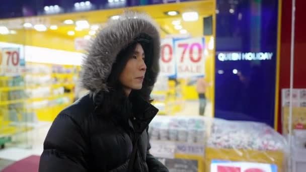 서울특별시 명동에서 차가운 나이트 마켓에서 걸어다니는 후드를 착용한 30대 — 비디오