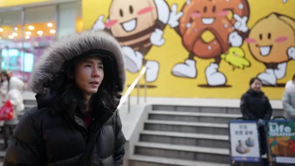 서울특별시 명동에서 차가운 나이트 마켓에서 걸어다니는 후드를 착용한 30대 — 비디오