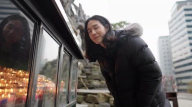 Myeong-dong, Seul, Güney Kore 'de soğuk bir kış günü kilisede tanrıça heykeline dua eden 30' lu yaşlarında uzun saçlı Koreli bir adamın yavaş çekim videosu.