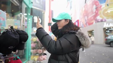 Myeong-dong, Seul, Güney Kore 'nin soğuk kışında 30' lu yaşlarında uzun saçlı Koreli bir adamın ana caddede alışveriş yaparken çekilmiş yavaş çekim videosu.