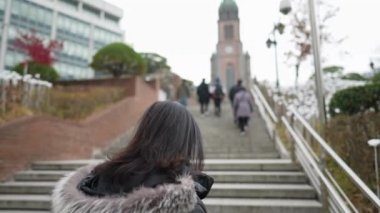  Myeong-dong, Seul, Güney Kore 'de soğuk bir kış günü kiliseyi ziyaret eden 30' lu yaşlarında uzun saçlı Koreli bir adamın yavaş çekim videosu.