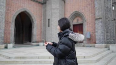  Myeong-dong, Seul, Güney Kore 'de soğuk bir kış günü kiliseyi ziyaret eden 30' lu yaşlarında uzun saçlı Koreli bir adamın yavaş çekim videosu.