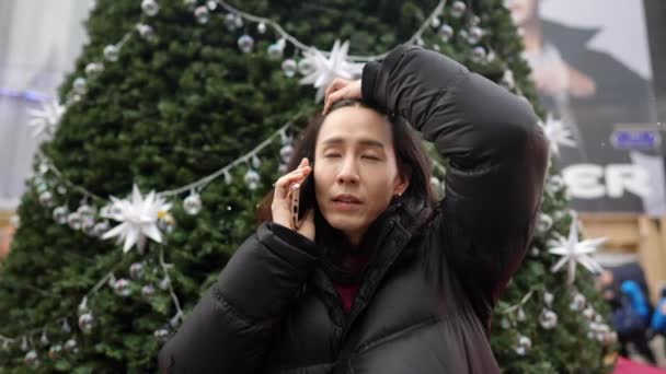 Slow Motion Video Koreańczyka Trzydziestce Rozmawiającego Przez Smartfona Przed Choinką — Wideo stockowe