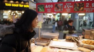 Myeong-dong, Seul, Güney Kore 'de soğuk bir kış gecesinde 30' lu yaşlarında Koreli bir adamın gece pazarında dolaşırken çekilmiş yavaş çekim videosu.