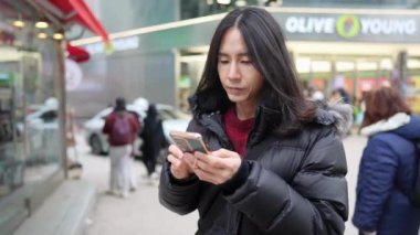 Myeong-dong, Seul, Güney Kore 'nin soğuk kışında akıllı telefonunu kullanan 30' lu yaşlarda Koreli bir adamın yavaş çekim videosu.